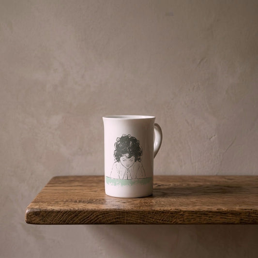 Heidi at the Table – porcelain art mug on an oiled oak shelf against a limewashed wall