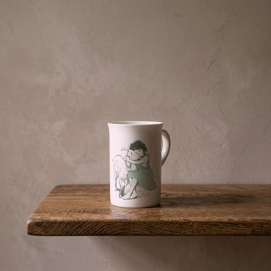 Heidi Hugging a Goat – porcelain art mug on an oiled oak shelf against a limewashed wall